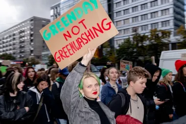 Young woman holding a sign that says greenday not greenwashing