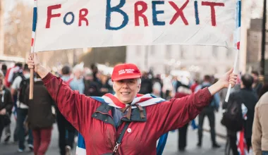 Een vrouw houdt een spandoek vast met de tekst "For Britain, For Brexit".