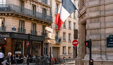 Photo montrant un drapeau français sur un bâtiment en béton gris près d'une route