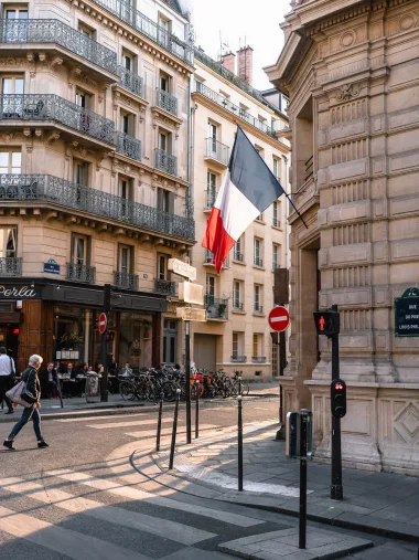 Photo showing a France Flag on Gray Concrete Building Near Road