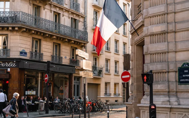 Photo montrant un drapeau français sur un bâtiment en béton gris près d'une route